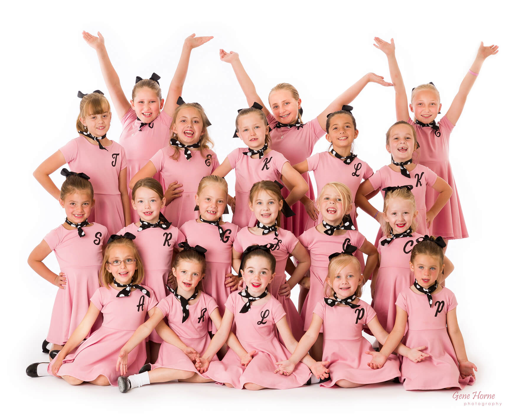 The girls in light pink dresses, wearing cheerful expressions.